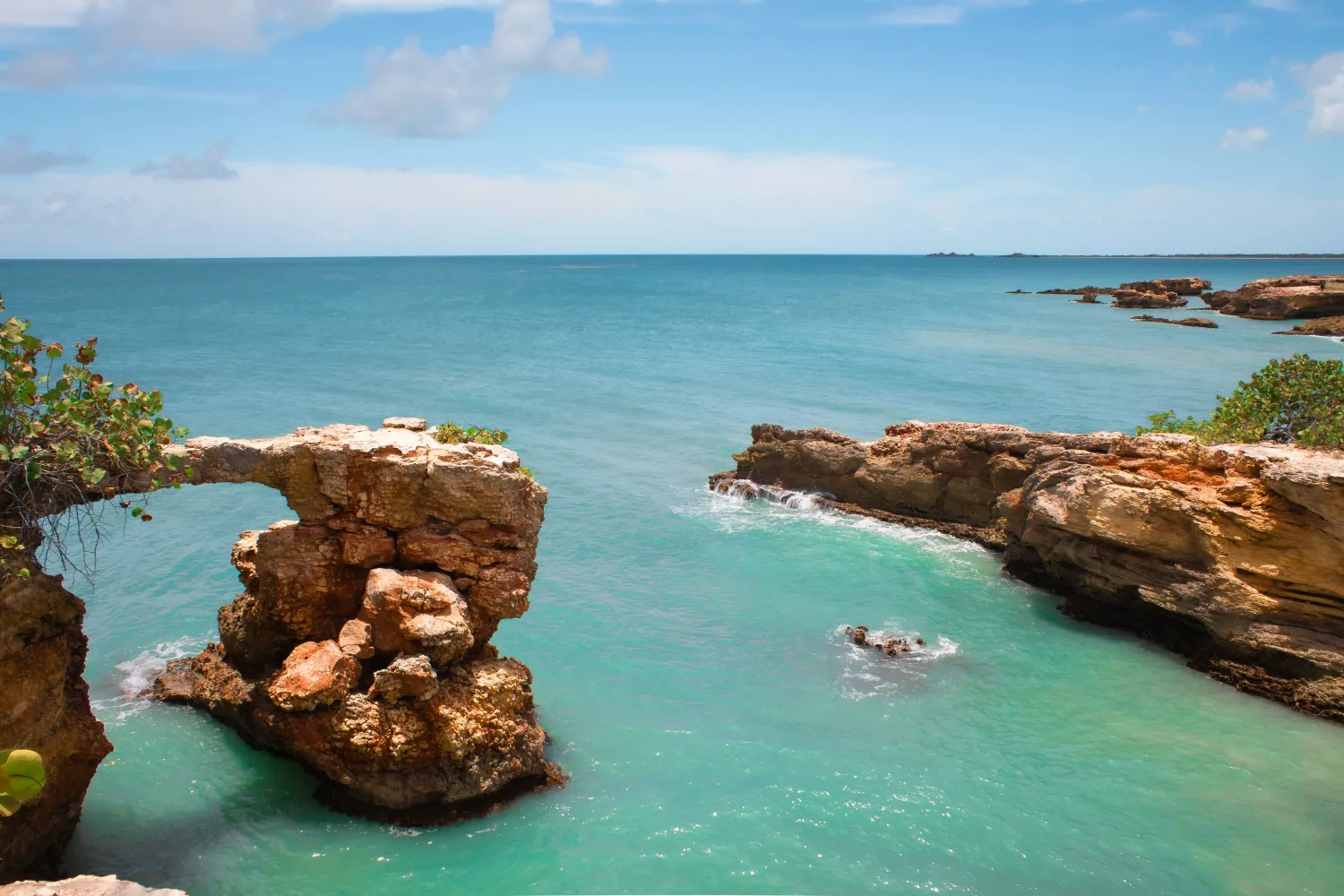 A natural rock arch in clear turquoise water off the Puerto Rico coast.