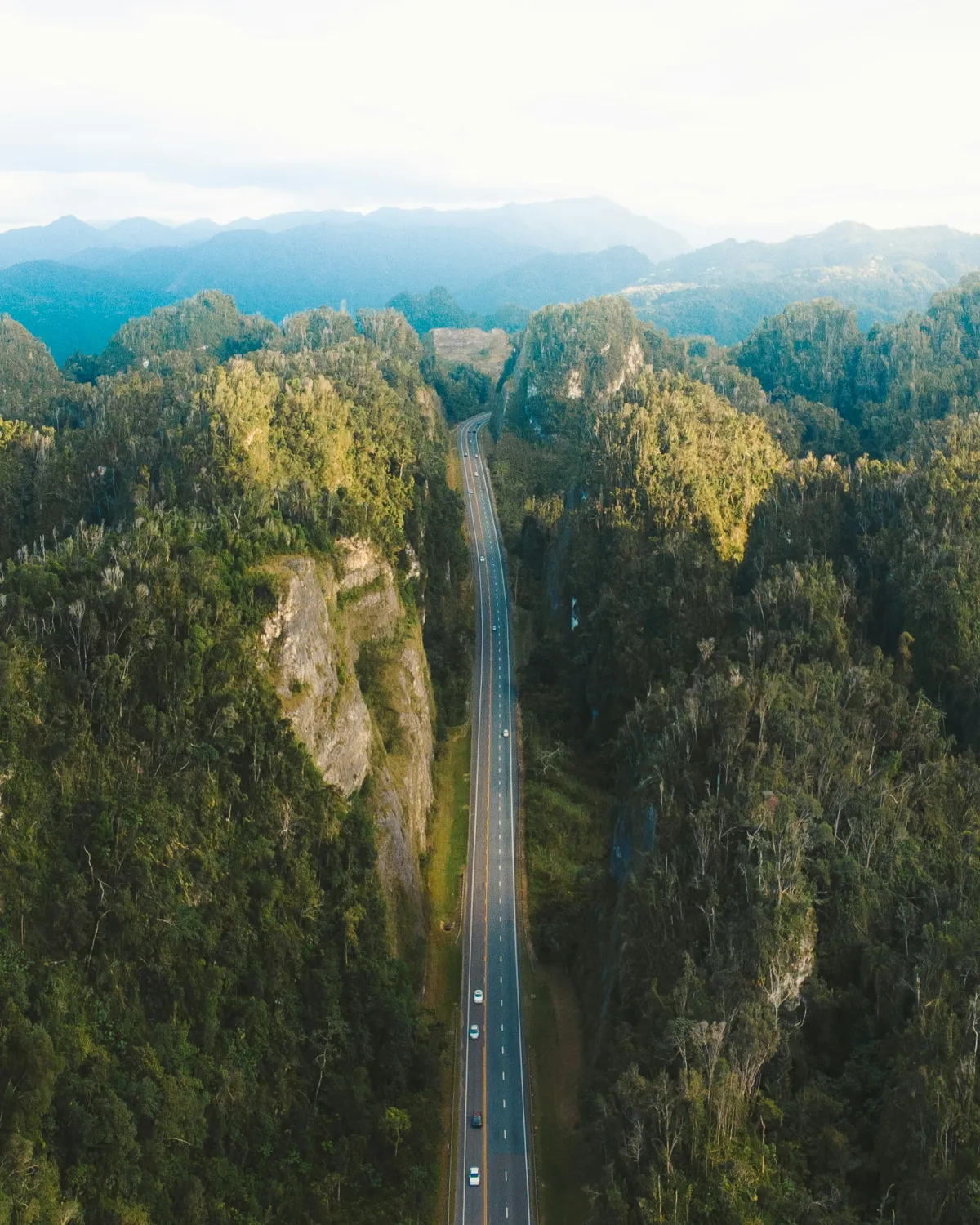 A quiet road winding through misty green mountains in Puerto Rico's interior.